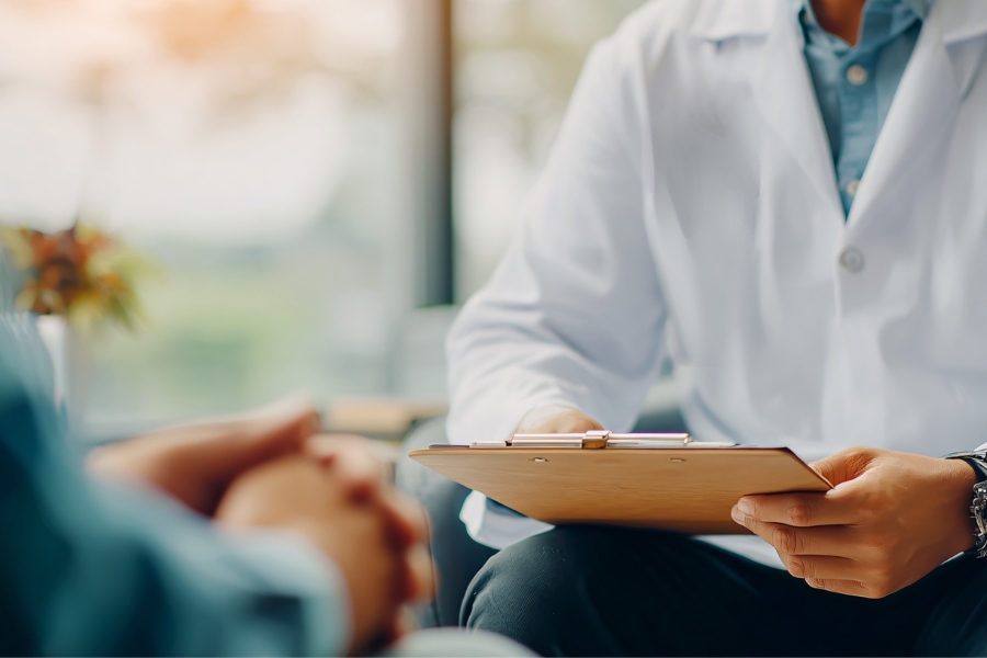 Doctor with a clipboard consulting with a patient about pathology results.